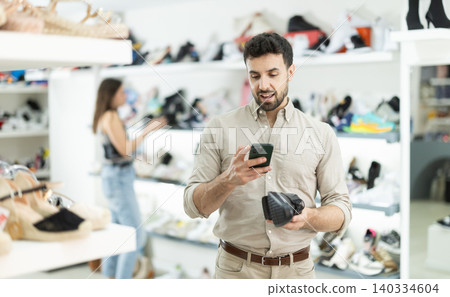 While shopping and choosing shoes, man scans QR code on classic shoes product While shopping and choosing shoes, man scans QR code on classic shoes product 140334604