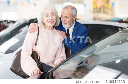 Elderly is standing in a car dealership Elderly is standing in a car dealership 140334613