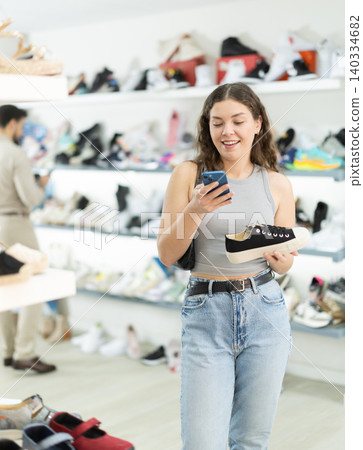 Woman paying for purchases by qr in shoe store Woman paying for purchases by qr in shoe store 140334682
