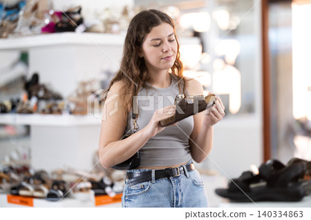 Woman shopper in shoe store is looking at summer sandals Woman shopper in shoe store is looking at summer sandals 140334863