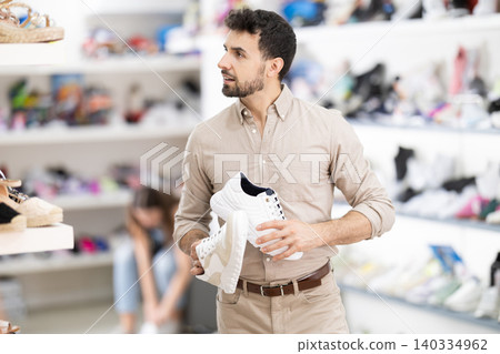 man chooses sneakers in a shoe store man chooses sneakers in a shoe store 140334962
