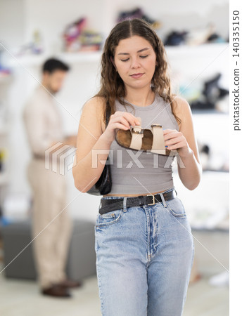 Young woman choosing sandals at footwear store Young woman choosing sandals at footwear store 140335150