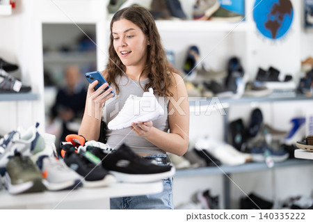 While shopping and choosing shoes, woman scans QR code on sneakers product While shopping and choosing shoes, woman scans QR code on sneakers product 140335222