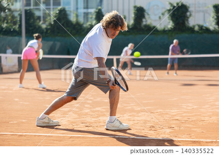 of young paddle tennis players enjoying double match. Positive man training serving ball of young paddle tennis players enjoying double match. Positive man training serving ball 140335522