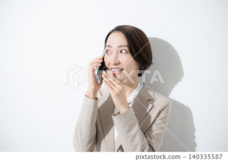 Close-up of businesswomen in suits secretly chatting on their smartphones, sharing reviews and word-of-mouth information. Close-up of businesswomen in suits secretly chatting on their smartphones, sharing reviews and word-of-mouth information. 140335587