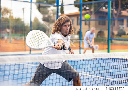 Focused man playing paddleball match on outdoor court Focused man playing paddleball match on outdoor court 140335721