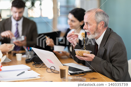 Senior male companys employees eat instant noodles, lunch time during break for staff Senior male companys employees eat instant noodles, lunch time during break for staff 140335739