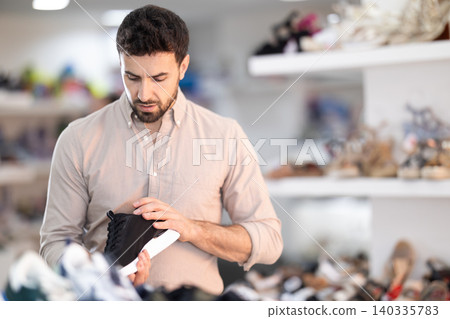 man chooses sneakers in a shoe store man chooses sneakers in a shoe store 140335783