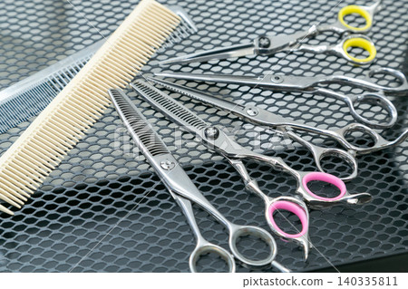 An overhead view of multiple cutting scissors and combs lined up on a cart in a hair salon. An overhead view of multiple cutting scissors and combs lined up on a cart in a hair salon. 140335811