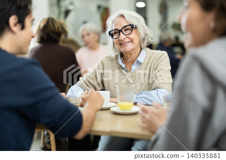 Large family is having breakfast in a cozy cafe, discussing news. Large family is having breakfast in a cozy cafe, discussing news. 140335881