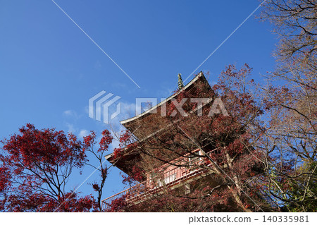 A multi-storied pagoda of a Buddhist temple in Kamitakano, northern Kyoto, against a backdrop of a blue sky. A multi-storied pagoda of a Buddhist temple in Kamitakano, northern Kyoto, against a backdrop of a blue sky. 140335981