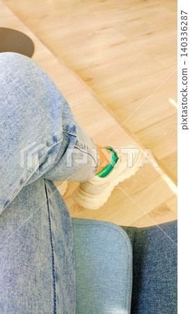 Casual Style: Person Wearing Blue Jeans and White Sneakers with Green Socks Sitting on Sofa - POV Shot 50 Keywords: Casual Style: Person Wearing Blue Jeans and White Sneakers with Green Socks Sitting on Sofa - POV Shot 50 Keywords: 140336287