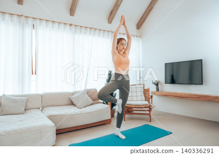 Young caucasian woman stretching yoga workout on exercise mat in living room at home Young caucasian woman stretching yoga workout on exercise mat in living room at home 140336291