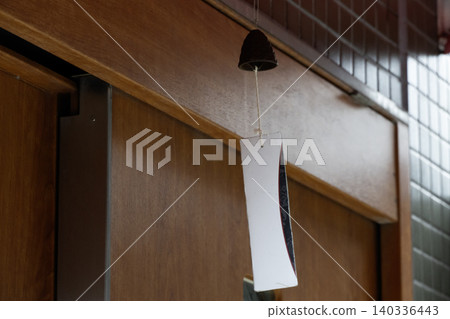 A simple wind chime hanging from a wooden door A simple wind chime hanging from a wooden door 140336443