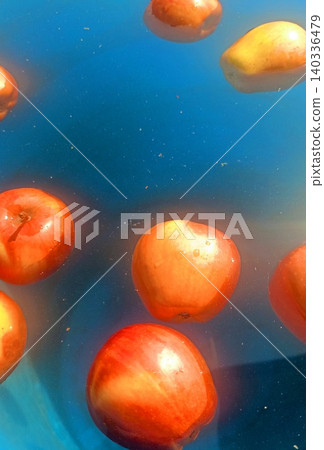 Red apples floating in blue water background with vibrant reflections 140336479