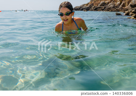 happy girl swimming in the blue sea with goggles happy girl swimming in the blue sea with goggles 140336806