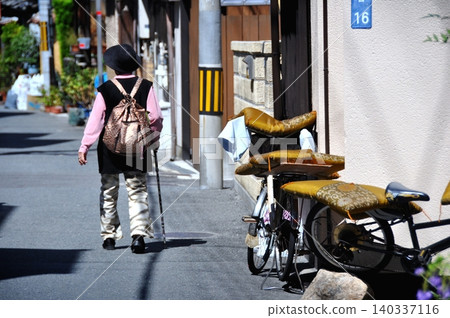 Senior woman walking in an alley Senior woman walking in an alley 140337116