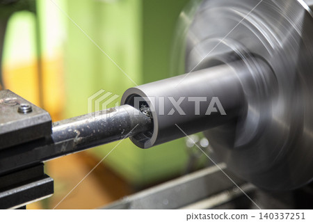 Close-up of a metal cylinder fixed to a lathe chuck undergoing internal diameter cutting. Close-up of a metal cylinder fixed to a lathe chuck undergoing internal diameter cutting. 140337251