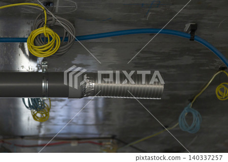 Metal flexible ducts and color-coded electrical wiring installed in the ceiling space of a building. (Building equipment installation) 140337257
