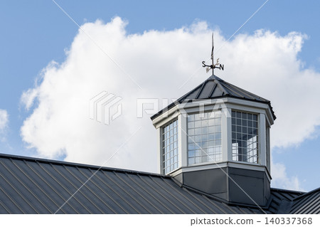 一座古典風格的建築,帶有風向標和尖頂,背景是藍天白雲。 一座古典風格的建築,帶有風向標和尖頂,背景是藍天白雲。 140337368