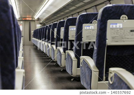 一張空蕩蕩的新幹線或特快列車的照片，車廂裡空無一人，座位和走道裡也空無一人。 140337692