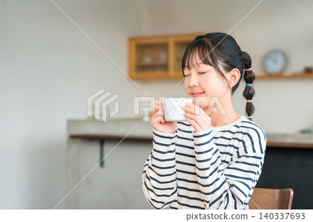 小學和中學的女孩們在家裡的客廳喝熱飲 小學和中學的女孩們在家裡的客廳喝熱飲 140337693