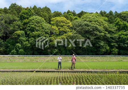Farmers standing along the field path 140337735