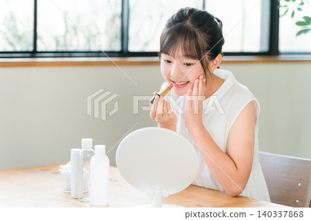 Children, girls, elementary school students, junior high school students applying lipstick while looking in the mirror 140337868