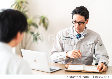 一位身穿工作服的男工程師和一位客戶困惑地看著文件。 一位身穿工作服的男工程師和一位客戶困惑地看著文件。 140337884