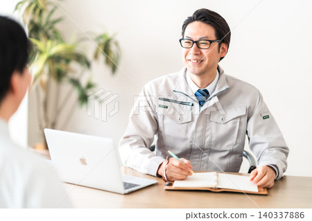 一位身著工作服的男工程師正在與客戶開會。 一位身著工作服的男工程師正在與客戶開會。 140337886