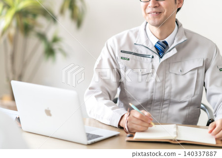 一位身穿工作服的男工程師和一位客戶正在開會;他們的臉都沒有露面。 一位身穿工作服的男工程師和一位客戶正在開會;他們的臉都沒有露面。 140337887