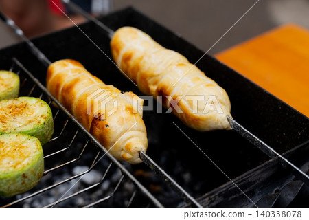 Chopped zucchini and khachapuri roasting on fire seasoned with aroma herbs and spices. Delicious fresh vegetables vegetarian grilling on barbecue smoker grid. Diet vegan bbq. Outdoor recreation 140338078