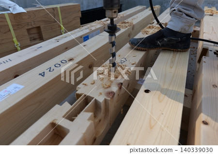 Japanese carpenter drilling holes in wooden foundation beam at construction site Japanese carpenter drilling holes in wooden foundation beam at construction site 140339030