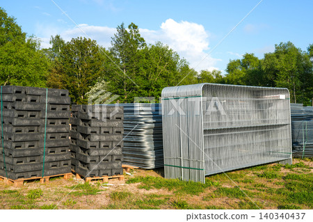 Temporary construction fencing panels and recycled plastic footings stored at construction yard site 140340437