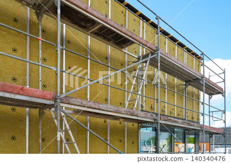 Mineral wool facade insulation and scaffolding on modern commercial building during construction Mineral wool facade insulation and scaffolding on modern commercial building during construction 140340476