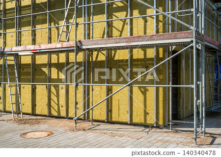 Mineral wool facade insulation installation with scaffolding on modern commercial building exterior Mineral wool facade insulation installation with scaffolding on modern commercial building exterior 140340478
