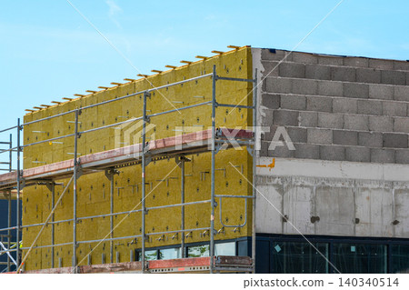 Mineral wool facade insulation installation on commercial building under construction project site 140340514