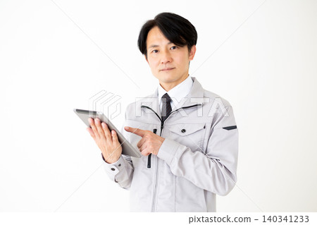 A middle-aged businessman in gray work clothes holding a tablet, against a white background. A middle-aged businessman in gray work clothes holding a tablet, against a white background. 140341233