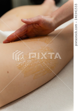 Therapist performs honey massage on client leg during wellness treatment. Therapist performs honey massage on client leg during wellness treatment. 140341533
