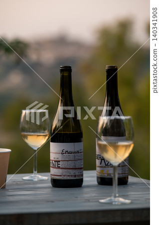 Sicilian natural wine bottles and glasses at golden hour outdoor table Sicilian natural wine bottles and glasses at golden hour outdoor table 140341908