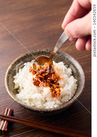 將辣椒油淋在米飯上。 將辣椒油淋在米飯上。 140342659