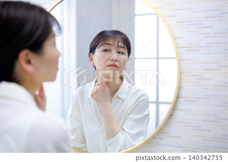 Senior woman looking in the mirror and worrying Senior woman looking in the mirror and worrying 140342735