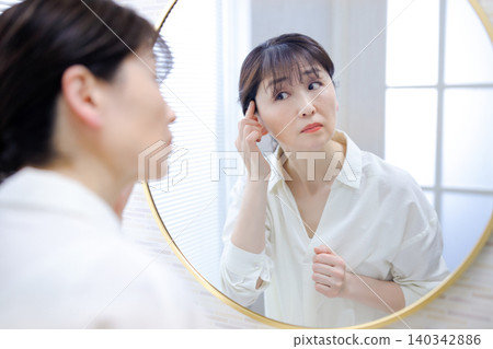 照鏡子時,會擔心自己髮際線後移的老年女性 照鏡子時,會擔心自己髮際線後移的老年女性 140342886