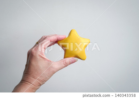 Hand holding a five point yellow star Hand holding a five point yellow star 140343358