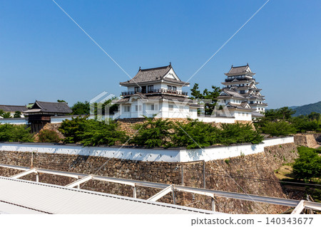 Fukuyama Castle's main tower and Fushimi turret as seen from the train platform against a blue sky background. 140343677
