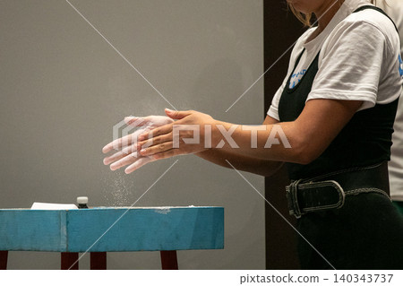 Female powerlifter applies talcum powder to her hands Female powerlifter applies talcum powder to her hands 140343737