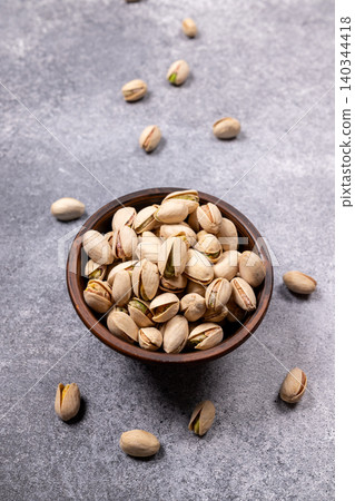 Pistachios in bowl on grey background, healthy snack food Pistachios in bowl on grey background, healthy snack food 140344418