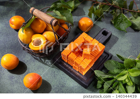 Apricot fruit leather blocks and fresh apricots on cutting board Apricot fruit leather blocks and fresh apricots on cutting board 140344439