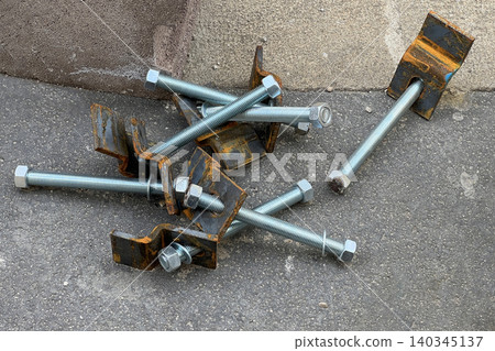 Close-up of steel bolts and rusty brackets on asphalt - industrial construction hardware, engineering, repair and maintenance concept Close-up of steel bolts and rusty brackets on asphalt - industrial construction hardware, engineering, repair and maintenance concept 140345137