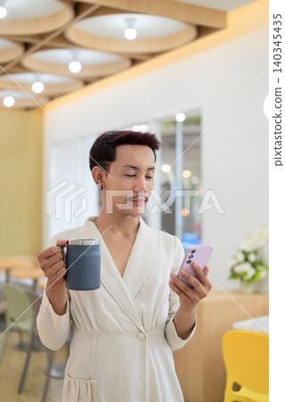 Vertical portrait of non-binary gay Thai man using smartphone and holding coffee mug at cafe Vertical portrait of non-binary gay Thai man using smartphone and holding coffee mug at cafe 140345435